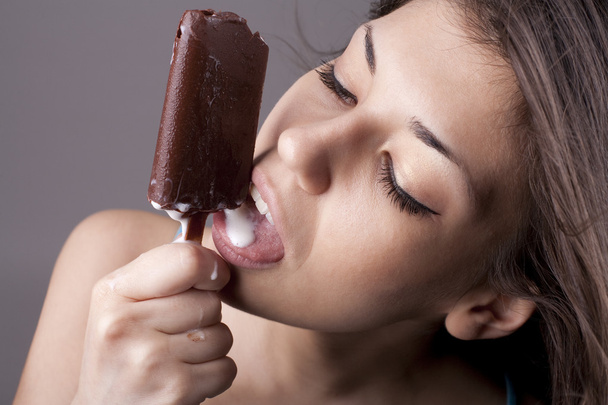 Σέξι μελαχρινή γυναίκα γλείφει παγωτό σοκολάτα - Φωτογραφία, εικόνα