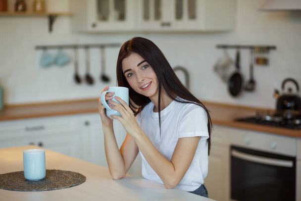 Beautiful young woman drinking a cup of coffee at home. - Фото, зображення