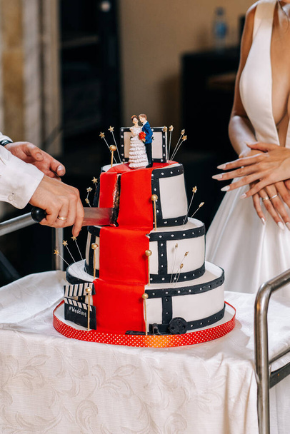 γαμήλια τούρτα λευκό τρεις ορόφους το στυλ του Hollywood κόκκινο χαλί ειδώλια νύφη γαμπρός - Φωτογραφία, εικόνα