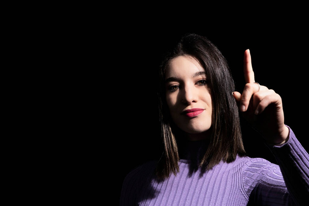 brunette woman showing the index finger on a black background pointing out that she is the best - Foto, Bild