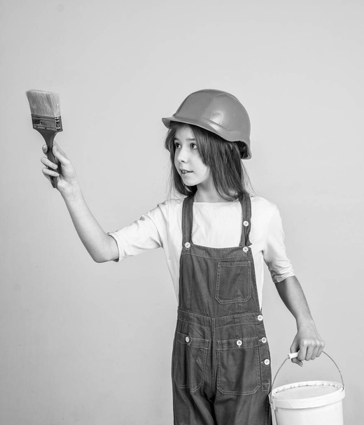 girl kid in hard hat on construction site use painting brush, builder - Фото, изображение