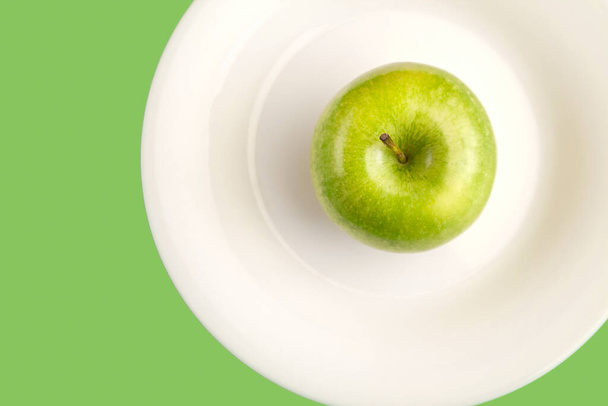 ホワイトプレートに緑のリンゴ。シンプルな健康的なライフスタイルフラットは、プレート上のリンゴとレイアウト. - 写真・画像
