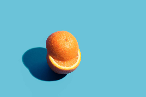 Pieces of cut orange on blue background with ree copy paste space. - Foto, Bild