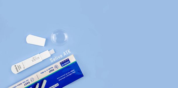 Saliva antigen test kit (ATK) for self-testing on isolated blue background. Covid-19 antigen test kit. Saliva SARS-CoV-2 antigen test kit. Copy space blank area for text. - Fotoğraf, Görsel