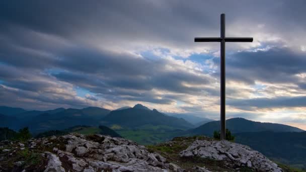 Cruz cristiana en una roca, hermoso paisaje de montaña con coloridas nubes gruesas 4K - Metraje, vídeo