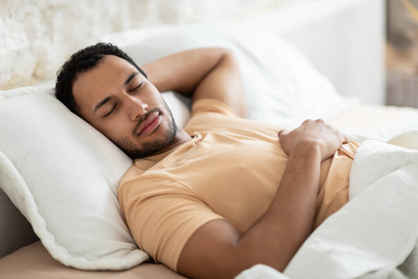 Oriente Medio hombre durmiendo acostado en la almohada en la cama interior - Foto, imagen