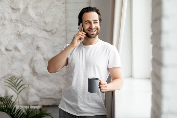 Ausgeruhter Mann telefoniert beim Kaffeetrinken - Foto, Bild