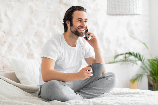 Relaxed man having phone call while drinking coffee - Foto, Bild