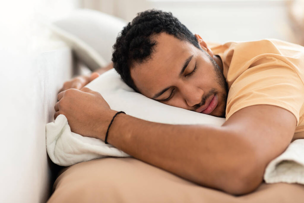 Oriente Medio Hombre durmiendo acostado en el estómago abrazando almohada en interiores - Foto, imagen