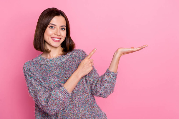 Portrait of attractive cheerful girl holding on palm demonstrating copy space ad gift isolated over pink pastel color background - Foto, Imagem