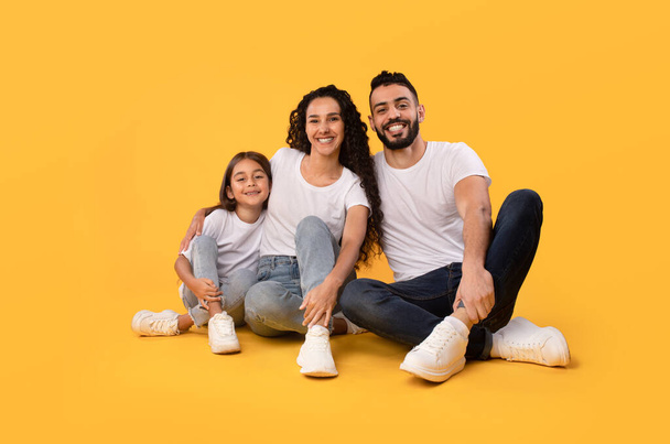 Middle Eastern Parents And Daughter Embracing Sitting On Yellow Background - Foto, Imagem
