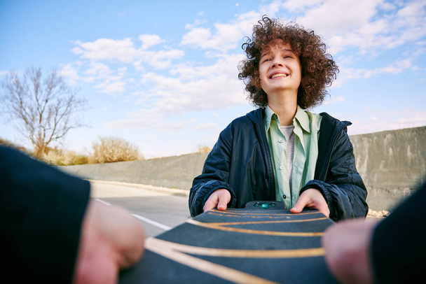 Un ami invite une adolescente à faire du skateboard. Amitié et concept d'invitation. - Photo, image