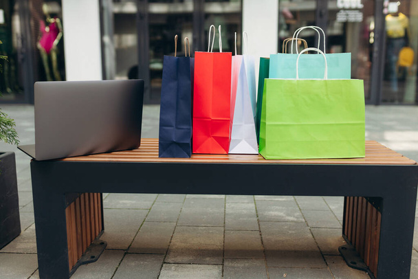 Laptop and shopping bags in the mall. Online shopping concept - Фото, изображение