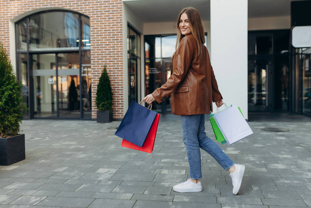 Mooi lachend meisje in het vasthouden van gekleurde tassen en geniet van haar winkelen. Winkelen verkoop lifestyle concept - Foto, afbeelding
