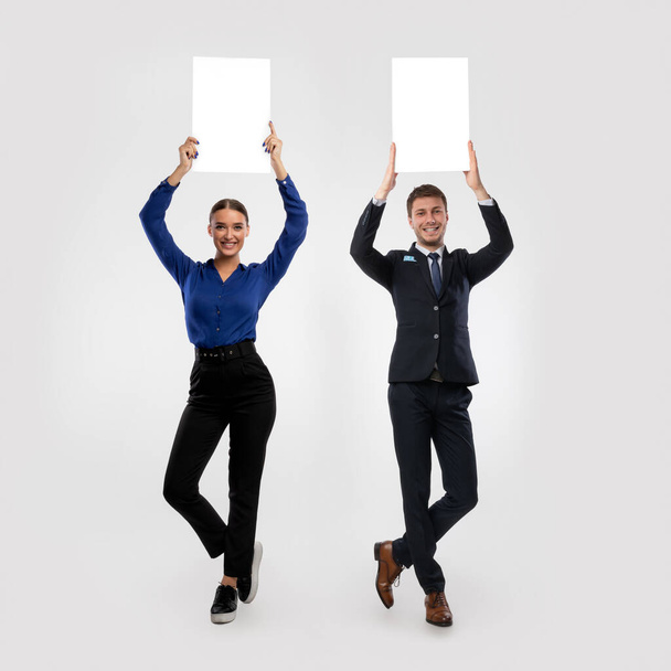 Two business people holding blank white advertising billboard at studio - Foto, afbeelding
