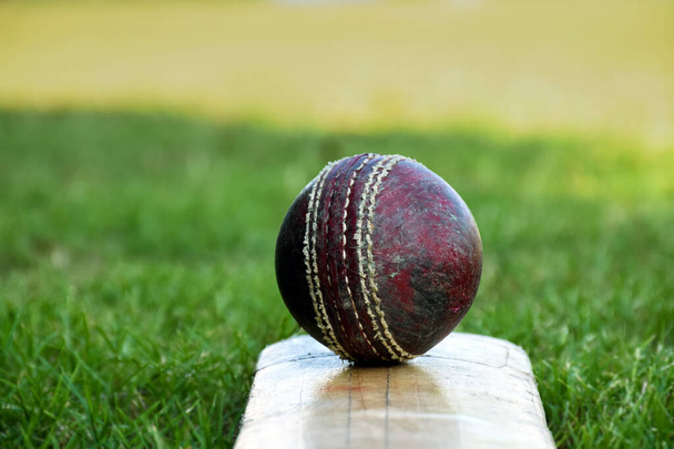Kriketové sportovní vybavení, starý kožený míč, dřevěný netopýr, helma na hřišti, měkké a selektivní zaměření. - Fotografie, Obrázek
