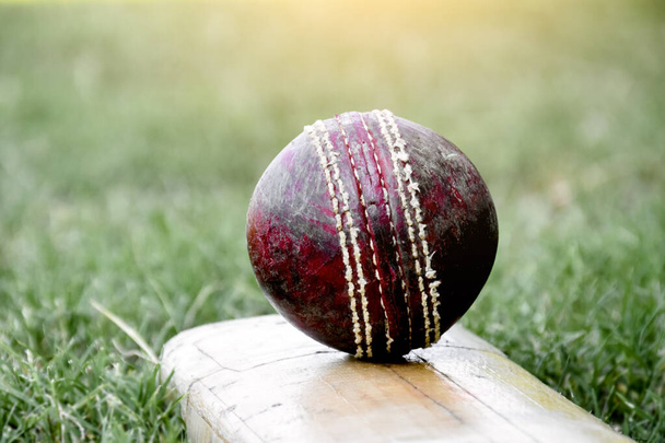 Спортивное снаряжение для крикета, старый кожаный мяч, деревянная летучая мышь, шлем на корте, мягкий и избирательный фокус. - Фото, изображение