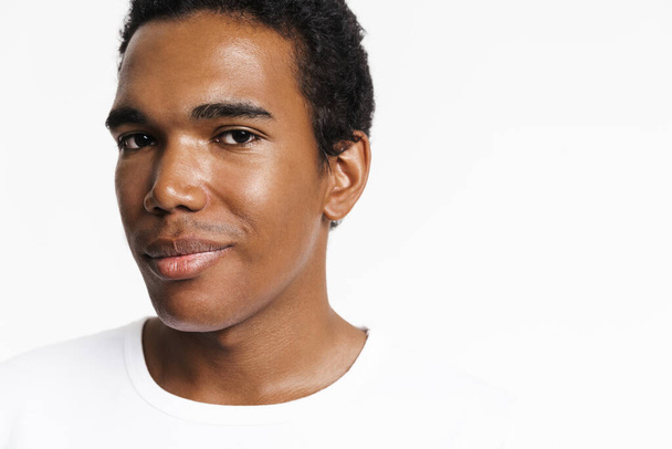 Young black man dressed t-shirt posing and looking at camera isolated over white wall - Photo, Image
