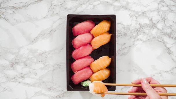 Flat lay. Pre-packaged variety of sushi and sushi rolls in a plastic tray. - Zdjęcie, obraz