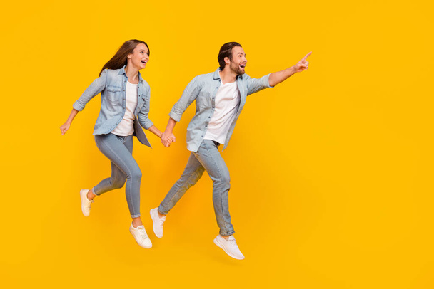 Full length body size view of beautiful handsome couple jumping showing copy space isolated over bright yellow color background - Foto, Imagem