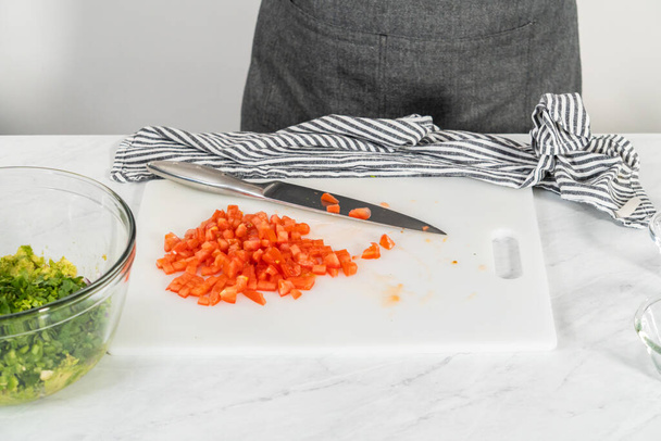 Cortar ingredientes en una tabla de cortar blanca para hacer salsa clásica de guacamole. - Foto, imagen