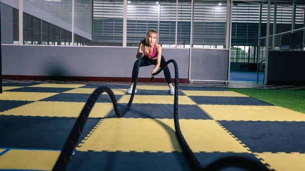 mujer asiática con cuerdas de batalla ejercicio en el gimnasio de fitness. gran ángulo de disparo - Foto, imagen
