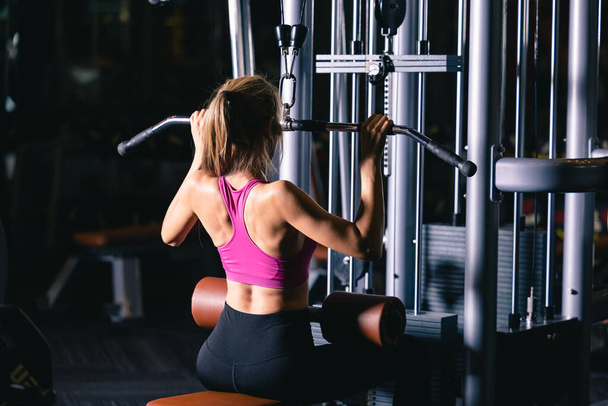 Fitness ασιατική γυναίκα εργάζονται στο γυμναστήριο κάνει άσκηση με επίκεντρο τους μυς χέρια και τους ώμους κινηματογραφική σκούρο τόνο, υγιή έννοια στυλ  - Φωτογραφία, εικόνα