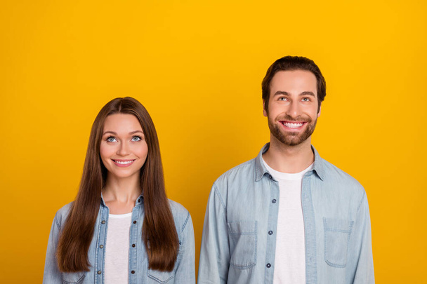 Photo of cool millennial brown hairdo couple look up wear jeans shirts isolated on yellow background - 写真・画像