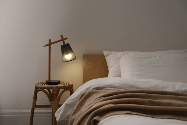 Stylish lamp on table near bed indoors - Foto, imagen