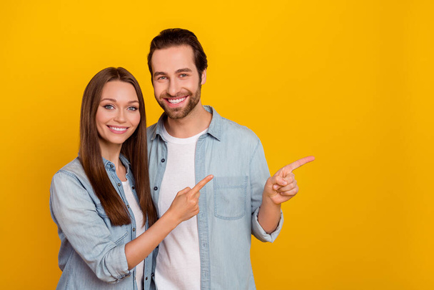 Photo of nice young brown hairdo couple index promo wear jeans shirts isolated on yellow background - Foto, Imagem