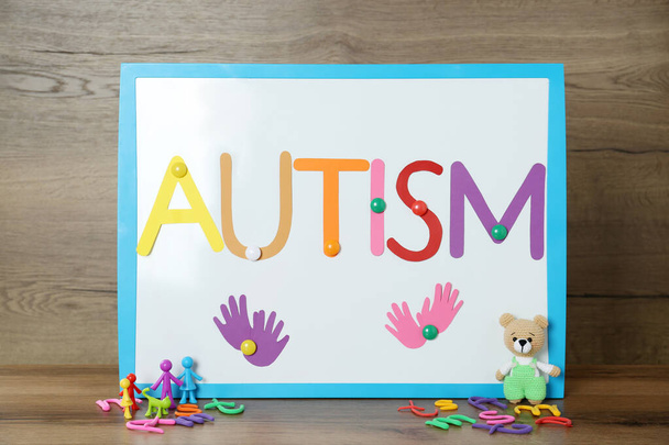 MYKOLAIV, UKRAINE - DECEMBER 30, 2021: Magnetic board with word Autism and toys on wooden table - Foto, Imagem