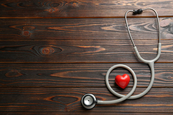 Stethoscope and red heart on wooden table, flat lay with space for text. Cardiology concept - Foto, afbeelding