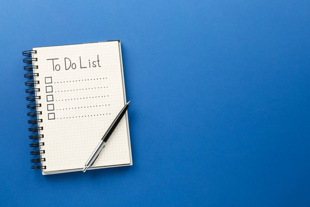 Notepad with unfilled To Do list and pen on blue background, top view. Space for text - Photo, Image
