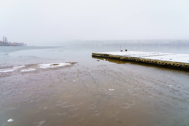 Egy folyó vagy víztározó ködös partja nedves hideg időben. Háttér másolási hellyel a szöveghez - Fotó, kép