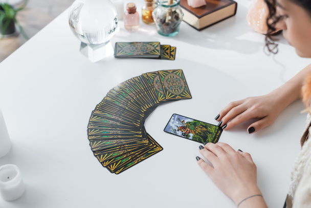 KYIV, UKRAINE - FEBRUARY 23, 2022: High angle view of blurred gypsy fortune teller looking at tarot cards  - Valokuva, kuva