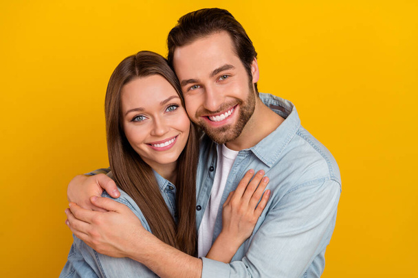 Photo of cheerful positive boyfriend girlfriend dressed denim shirts embracing smiling isolated yellow color background - Foto, imagen