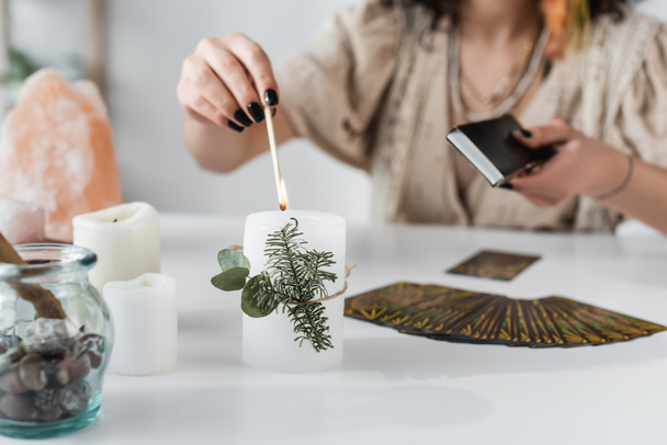 Cropped view of medium burning candle near tarot cards on table  - 写真・画像