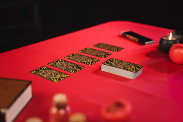 KYIV, UKRAINE - FEBRUARY 23, 2022: Tarot near candles and blurred book on table isolated on black  - 写真・画像