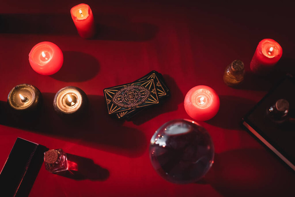 KYIV, UKRAINE - FEBRUARY 23, 2022: top view of tarot cards near candles and witchcraft supplies on table  - 写真・画像