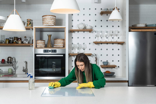 Young landlady is making a big cleaning for the apartment she is renting out, to be clean for the new tenants to whom she has rented out the apartment. Teenage girl or woman rubbing the kitchen. - Foto, Bild