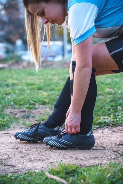 Футболистка, завязывающая шнурки на кроссовки - Фото, изображение