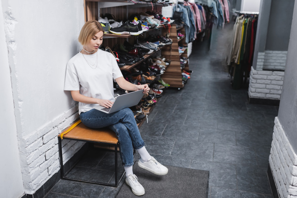 Blonde retailer using laptop near shoes in vintage shop  - Fotografie, Obrázek