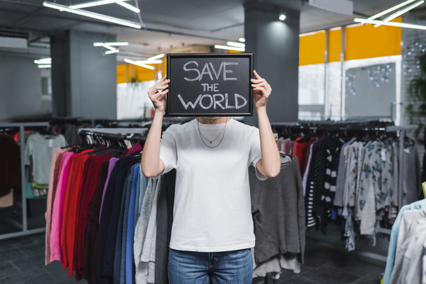 Retailer holding board with save the world lettering in second hand  - Foto, Imagen