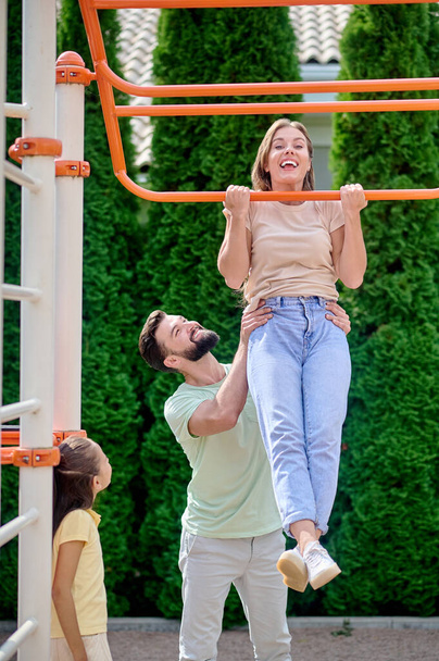 A family having fun at the sports gound on horizontal bar - Foto, immagini