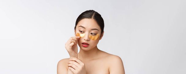 Asijské krása teenager žena péče ji kůže se zlatým okem masky skvrny pod očima - Fotografie, Obrázek