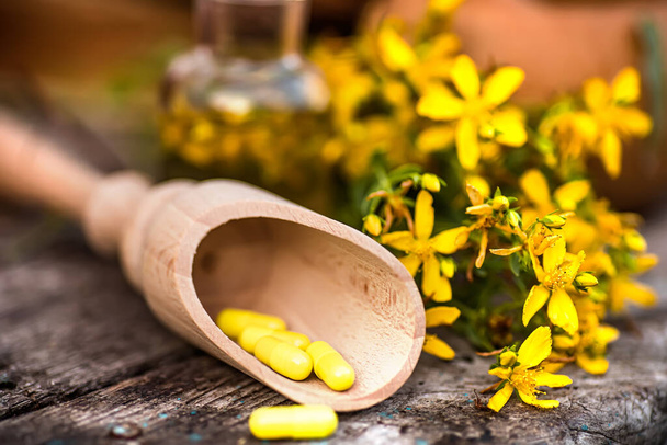 St. John otu. Bitkisel ilaç. Hypericum bitkileri alternatif tıpta kullanılan sarı çiçekleri eski bir masadaki ahşap bir tabakta. Homeopatik tedaviler için tıbbi bitkiler Hypericum. Üst görünüm - Fotoğraf, Görsel