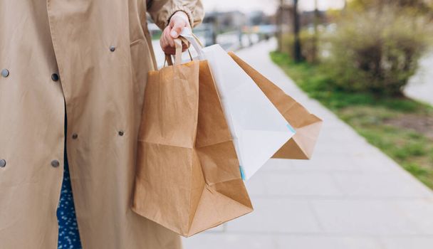 Cropped view of woman in autumn wear holding shopping paper bags in hands, walking at street, black friday. Urban lifestyle concept. Delivery carrying. - Φωτογραφία, εικόνα