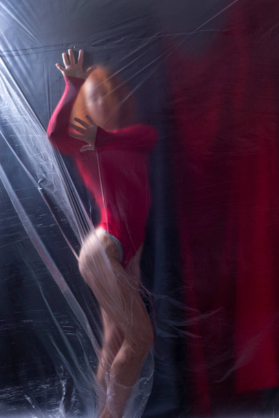 szexi lány sportoló egy piros testruha egy sötét háttér. - Fotó, kép