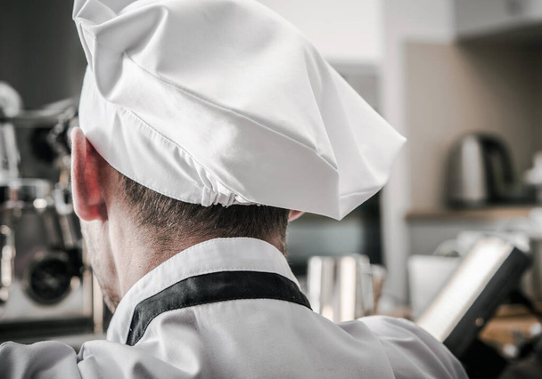 Chef de cuisine caucasien portant un chapeau Vue arrière Gros plan. Thème de l'industrie gastronomique. - Photo, image
