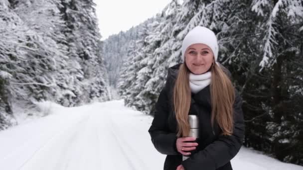 La chica sostiene la nieve en sus manos y la sopla, se divierte en el bosque de invierno.  - Metraje, vídeo